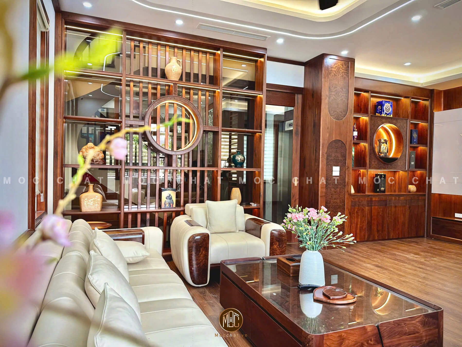 Phòng khách gỗ óc chó cao cấp với bộ bàn ghế gỗ óc chó bọc da bò Ý, bàn trà mặt kính, vách ngăn trang trí gỗ óc chó đậm chất nghệ thuật và sàn gỗ tự nhiên.