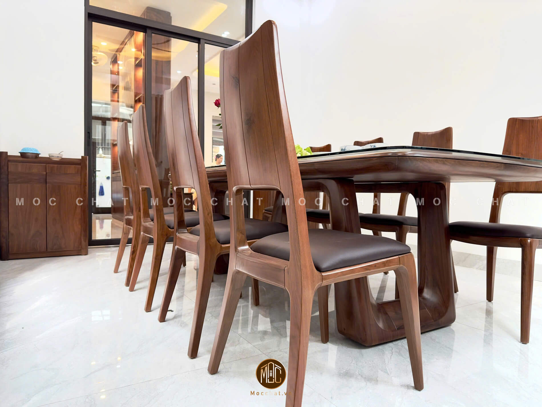 Bộ bàn ăn gỗ óc chó 8 ghế thiết kế bo cong tinh tế, chân bàn liền khối, ghế lưng cao với đệm da bò sang trọng, phù hợp phòng ăn hiện đại