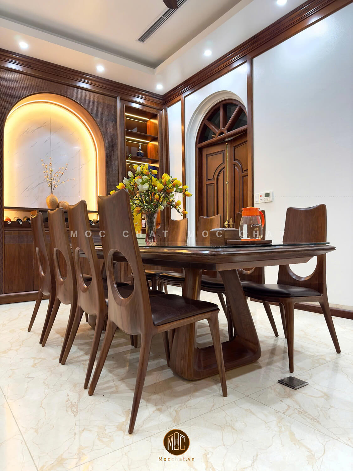 Bàn ghế ăn gỗ óc chó 8 ghế cao cấp với thiết kế ghế lưng cong khoét tròn và bàn mặt kính cường lực